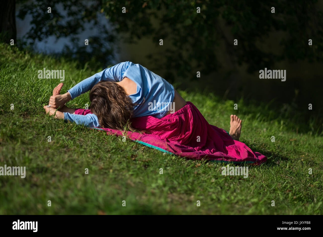 Femme pratique le yoga asana dans parc dans la matinée. Banque D'Images