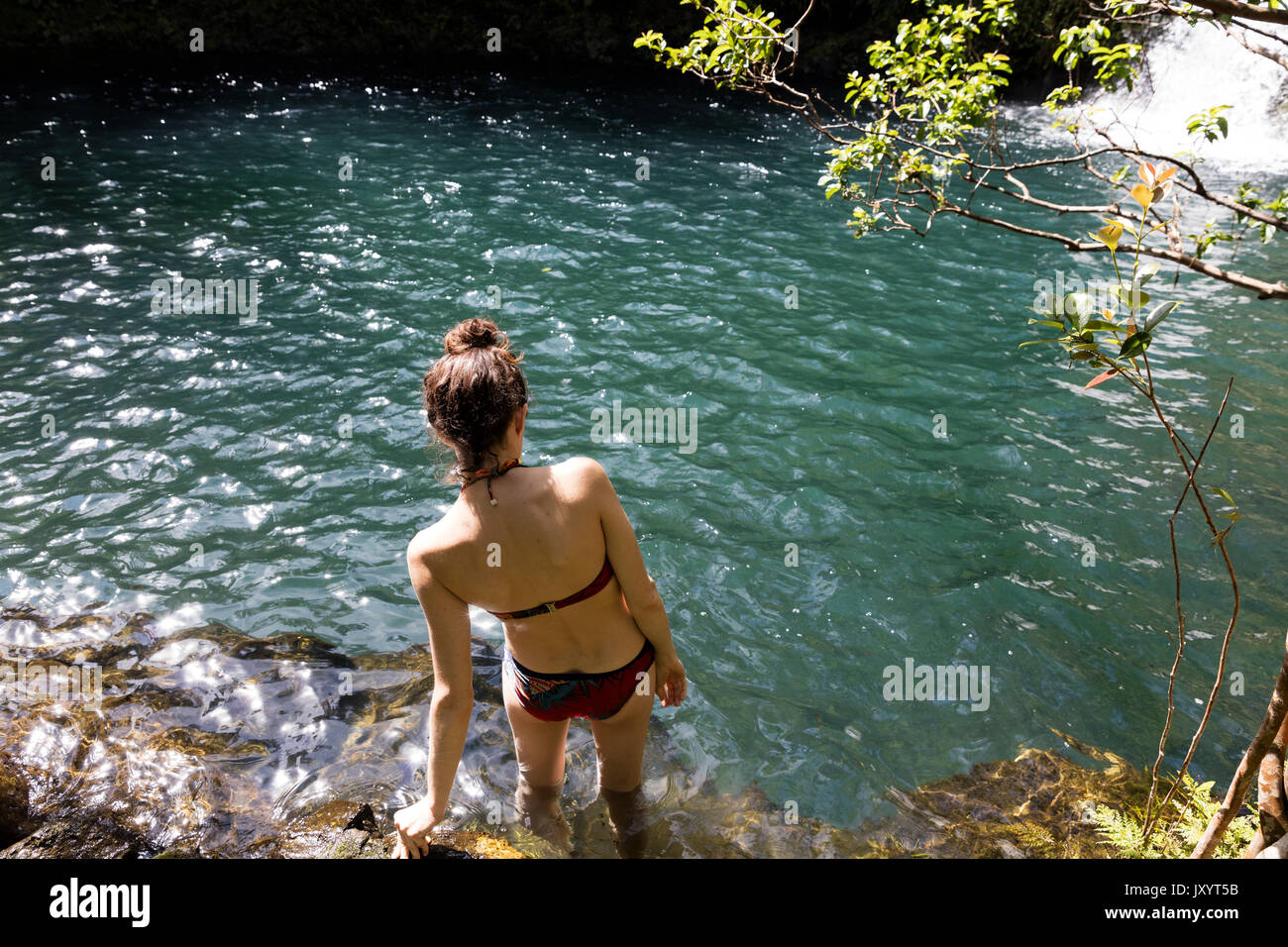 Caucasian woman wading in pool near waterfall Banque D'Images