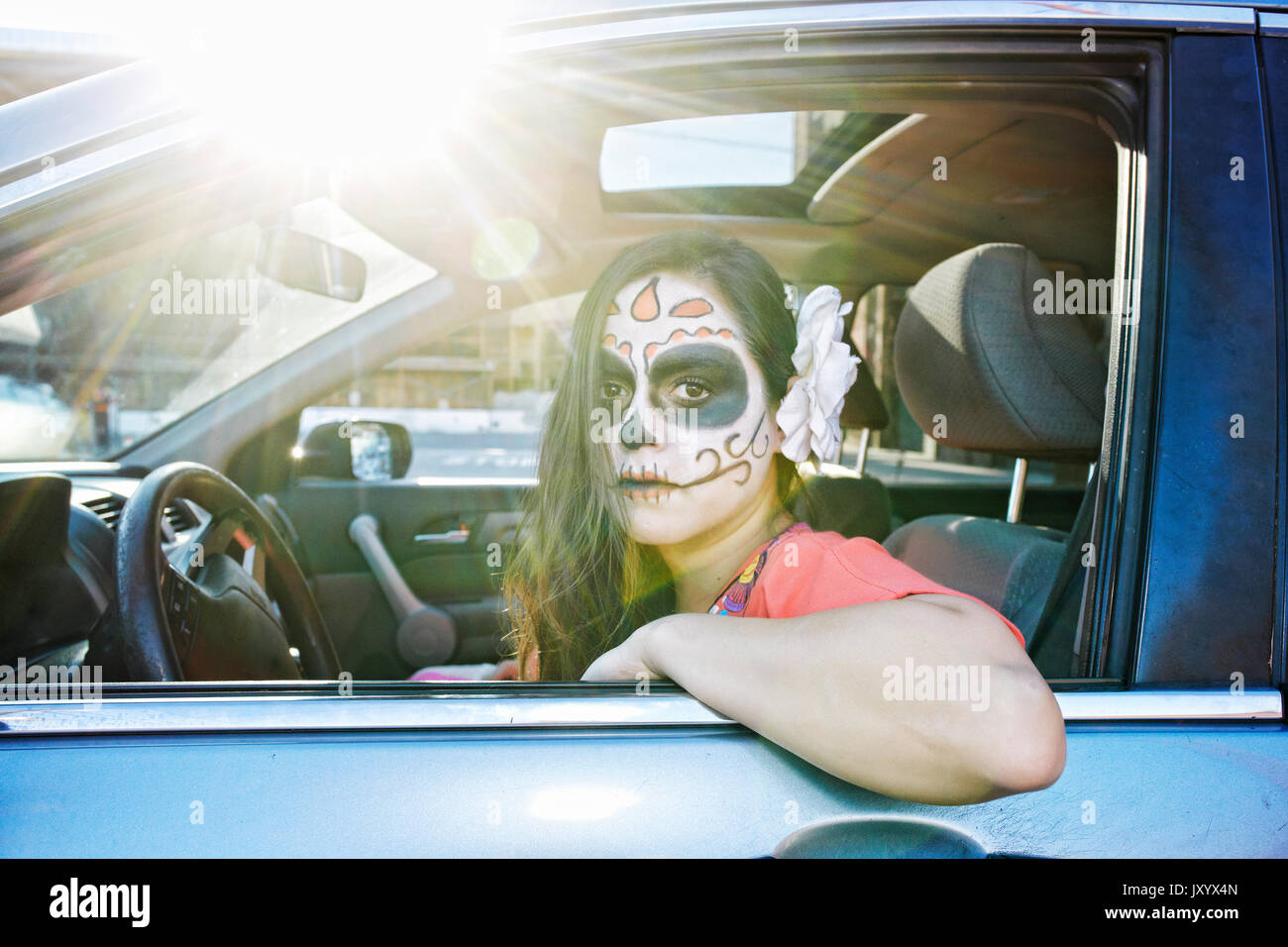 Hispanic woman driving car le port de crâne face paint Banque D'Images