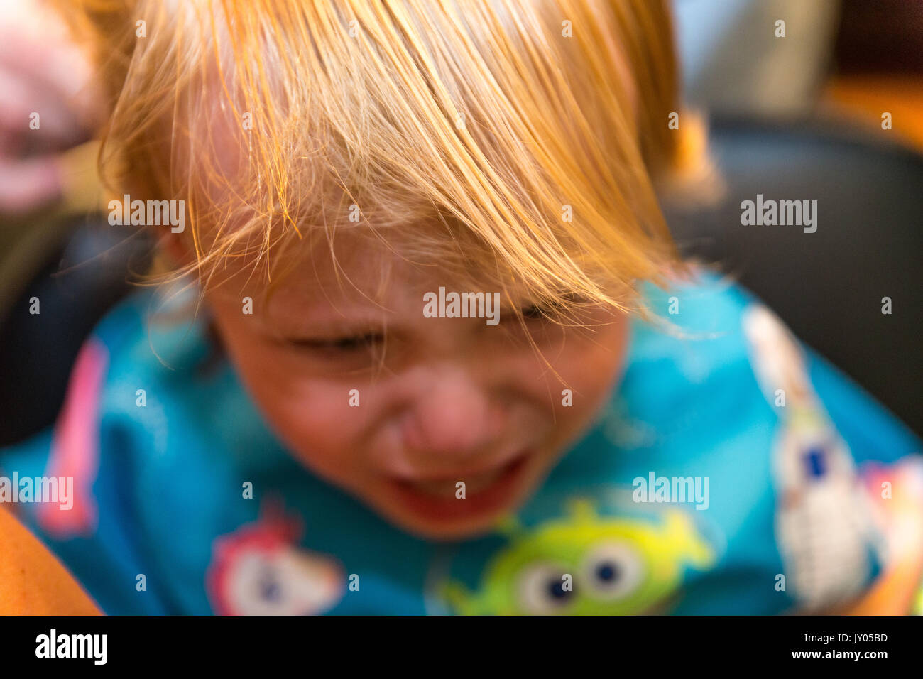 Portrait Bébé garçon s'assied et pleure pendant qu'il se fait couper les cheveux Banque D'Images