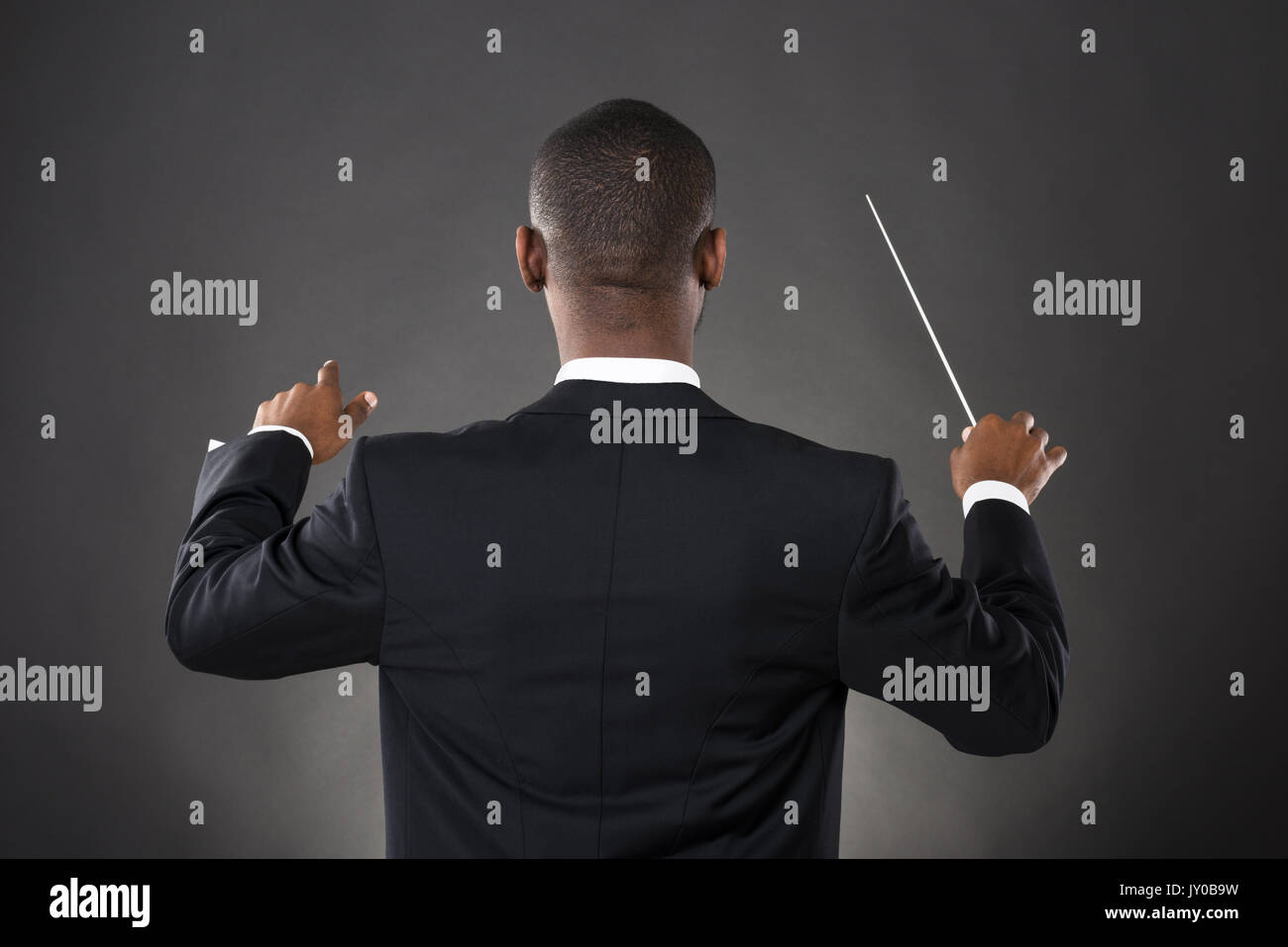 La direction d'orchestre de jeunes Africains avec son bâton sur fond noir Banque D'Images