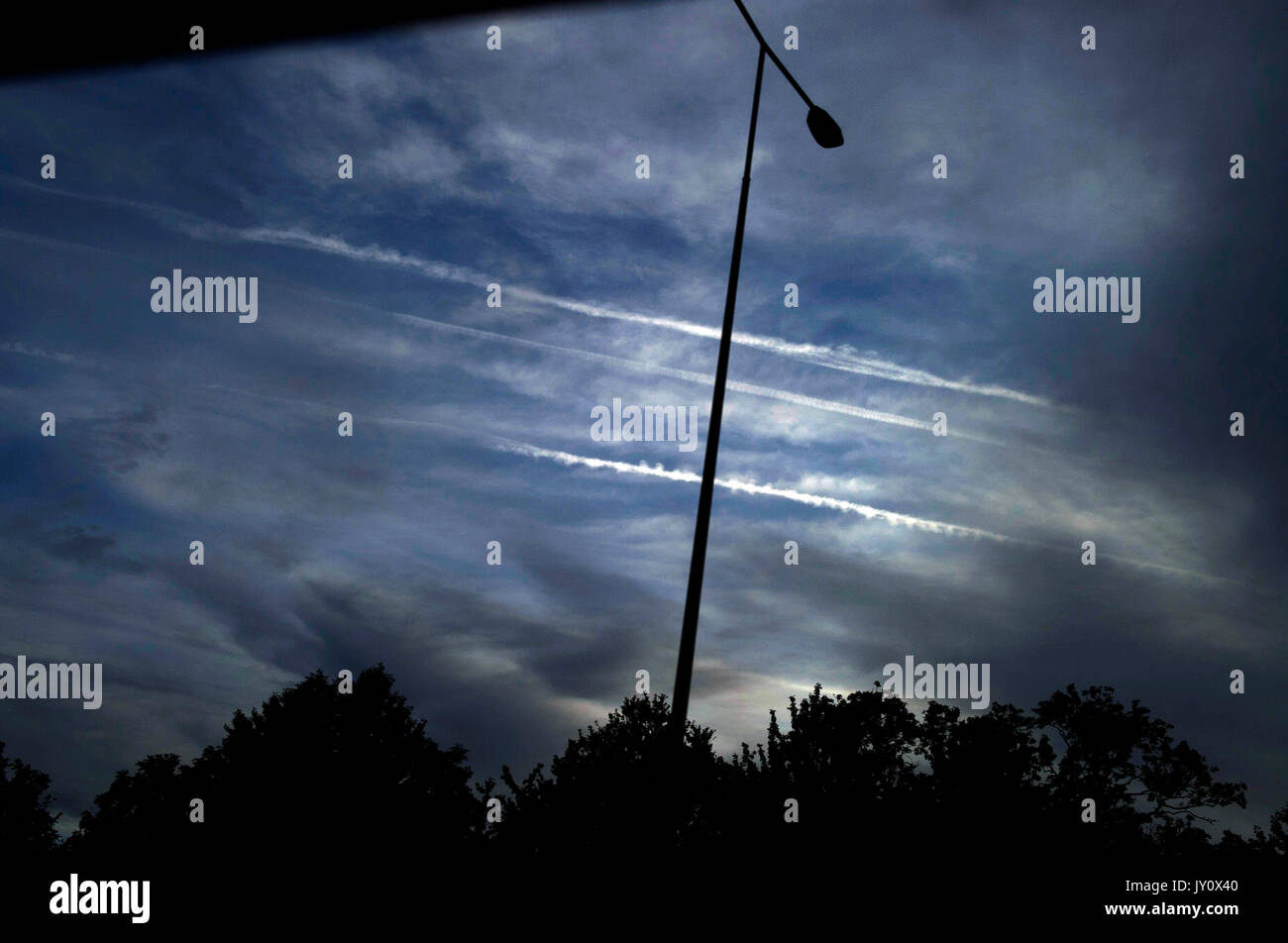 Les traînées d'avion dans le ciel au-dessus d'ossature d'un lampadaire lumière Banque D'Images