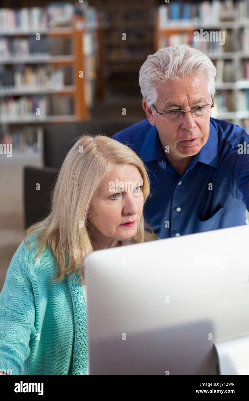 Homme plus âgé aider woman in library Banque D'Images