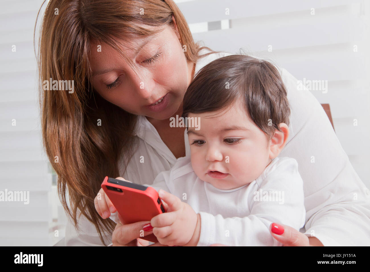 Hispanic mother holding baby boy playing with cell phone Banque D'Images