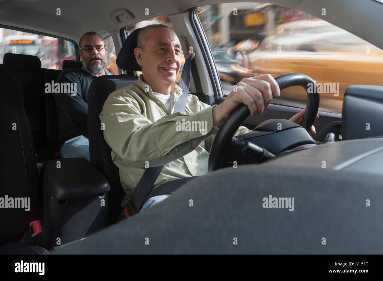 Smiling Hispanic man driving car avec passager Banque D'Images