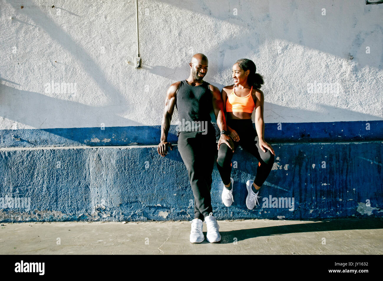 Couple assis sur le rebord du mur urbain Banque D'Images