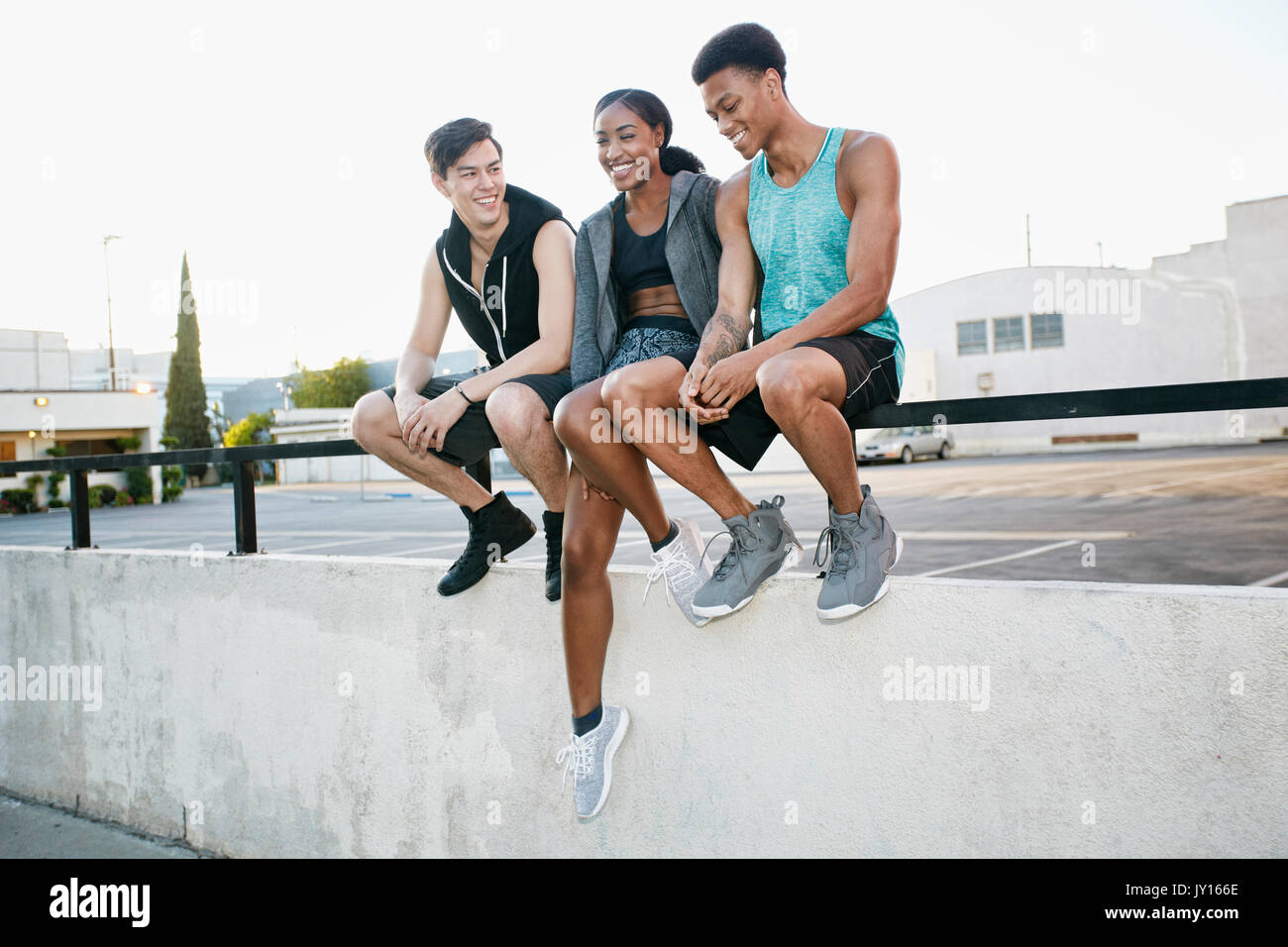 Amis assis sur main courante en stationnement Banque D'Images