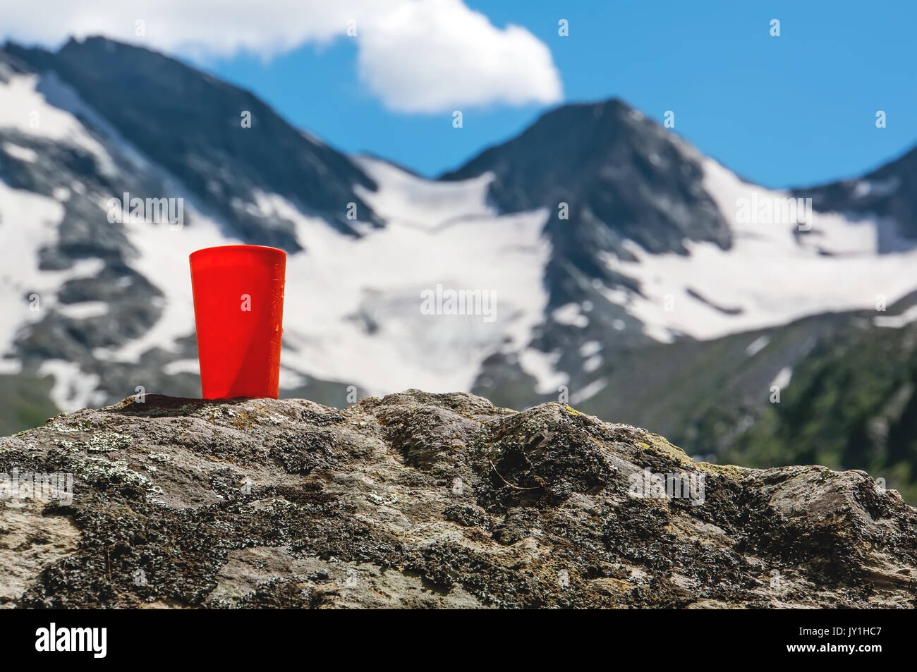 Orange un verre d'eau sur les pierres, sur fond flou belles montagnes. La notion de fraîcheur et de la pureté de la nature sauvage. Banque D'Images