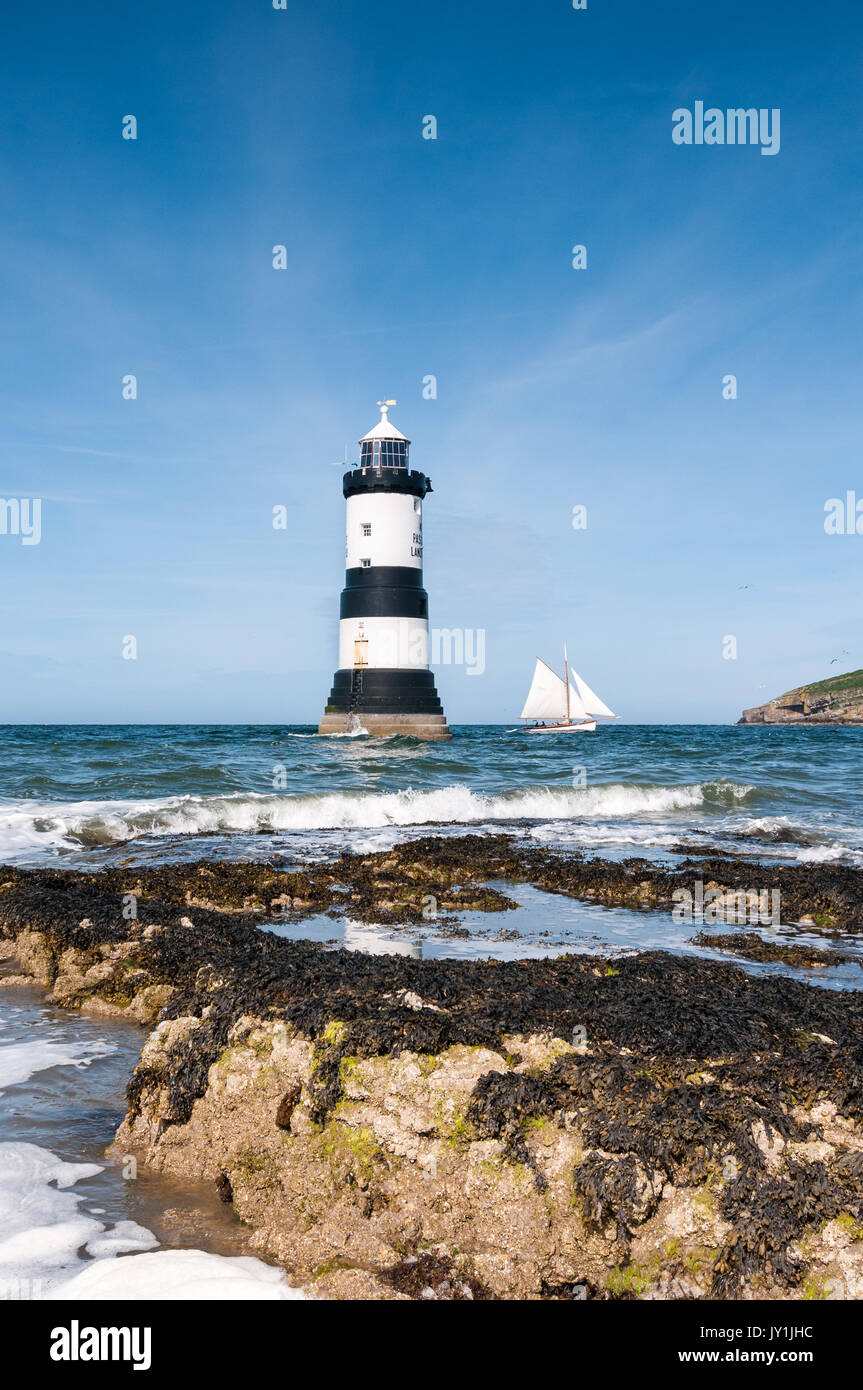 Penmon phare avec la voile en passant par, Anglesey, Pays de Galles, Royaume-Uni Banque D'Images