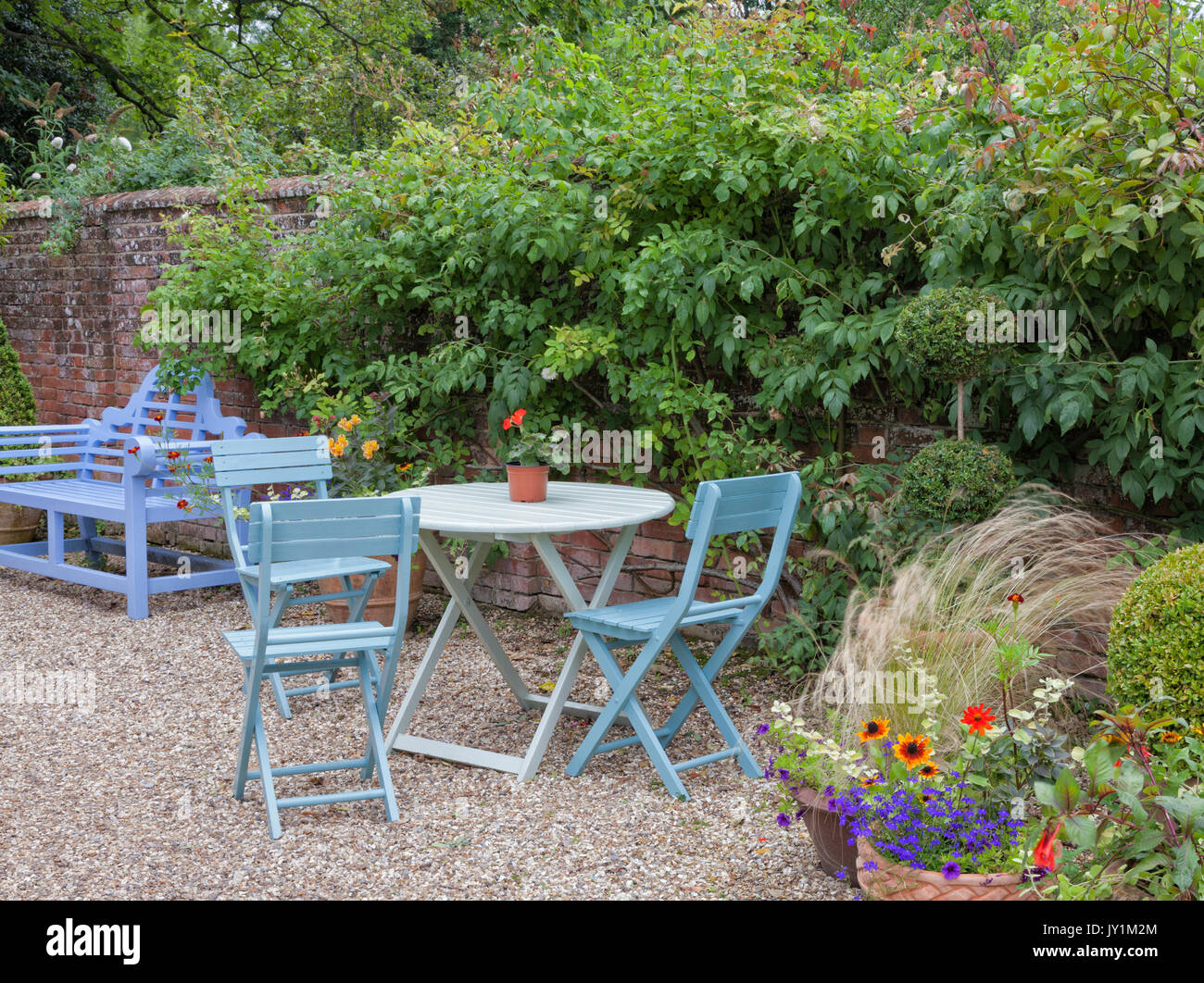 Bleu banc, table et chaises par un mur dans un cottage anglais, le jardin d'été . Banque D'Images