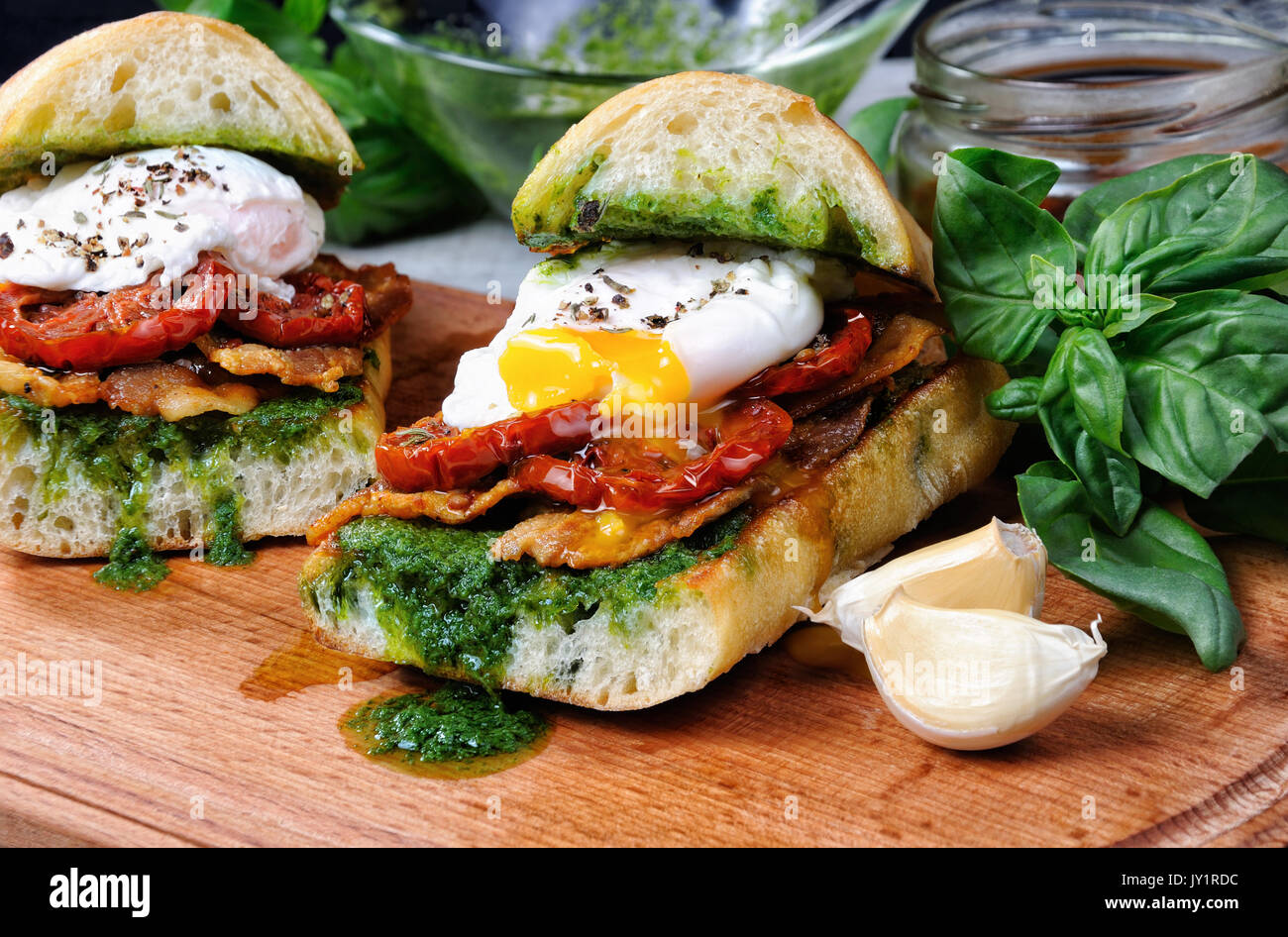 Ciabatta grillé au pesto, tranches de bacon, tomates séchées au soleil et œuf poché Banque D'Images