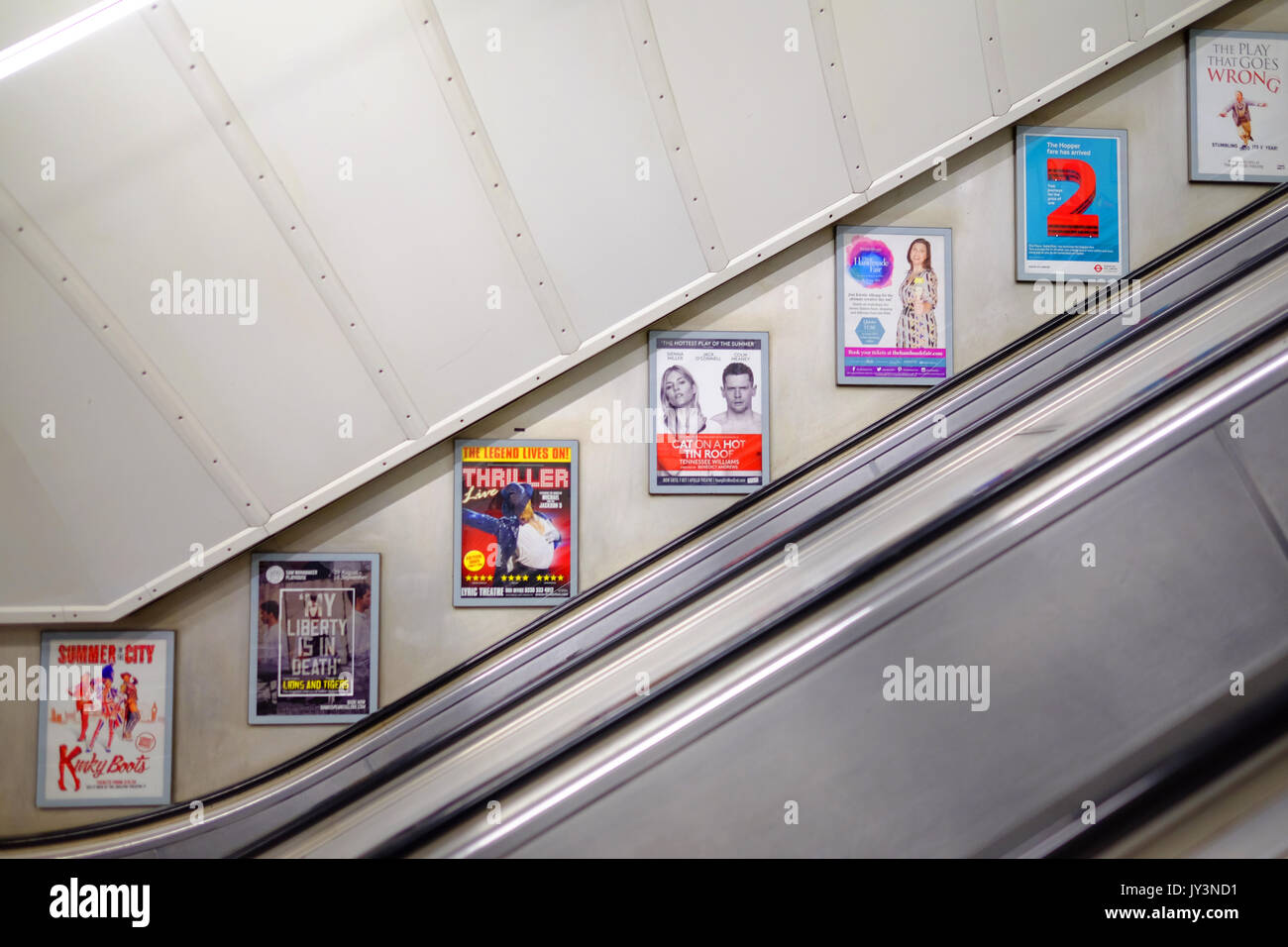 Les panneaux publicitaires sur le mur de l'escalier mécanique à une station de métro de Londres. Banque D'Images
