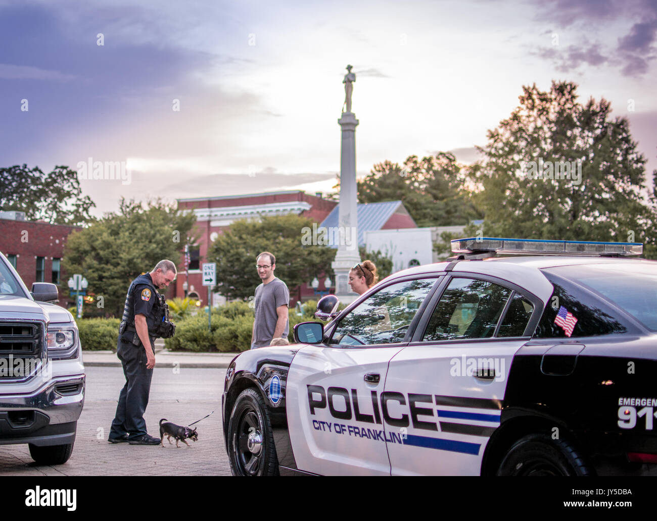 Nashville, Tennessee, USA. 17 août, 2017. Un agent de police Franklin accueille un chihuahua dog et une famille en face de la Confederate Monument à la place publique de Franklin, Tennessee, USA. Au cours des derniers jours, les menaces de détruire les statues des confédérés ont été réalisés, ce qui a incité la police à renforcer leur présence. Crédit : Jim Diamond/Alamy Live News. Banque D'Images