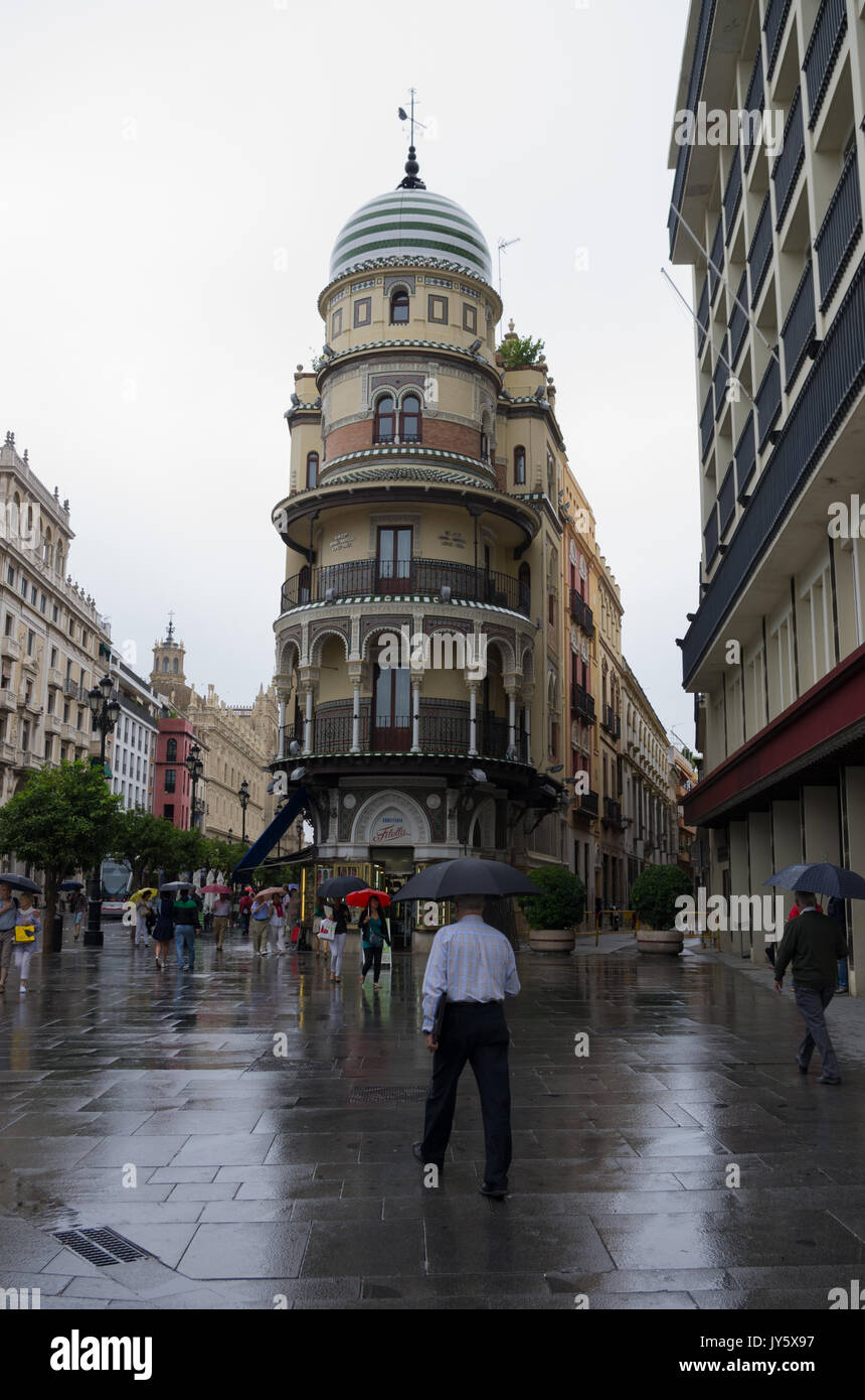 Pleuvoir à Séville avec l'homme avec umbrella walking in Cánovas del Castillo, avec la Adriática Building, Séville, Espagne Banque D'Images