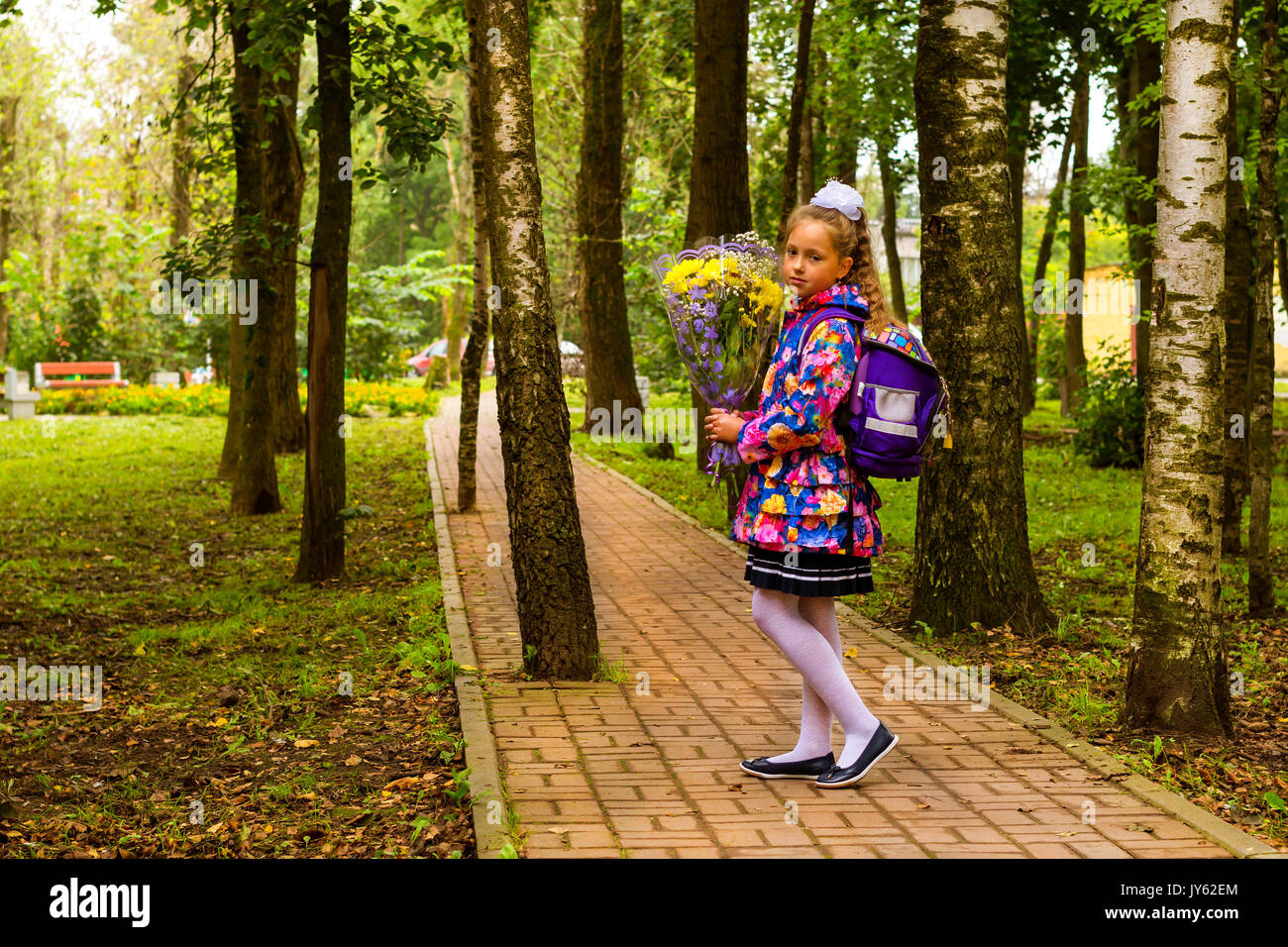 Peu d'abord élève, étudiant-fille va à l'école sur le savoir jour 1. Septembre. Élève de l'école élémentaire en uniforme avec des fleurs en automne Banque D'Images