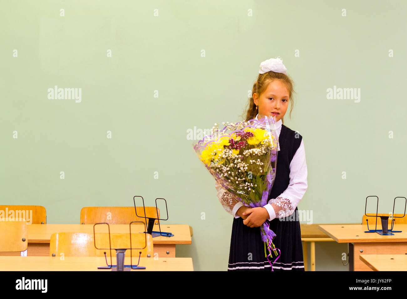 Peu d'abord-niveleuse, girl-étudiant à l'école sur le savoir - jour 1. Septembre. Élève de l'école élémentaire en uniforme avec des arcs posant en classe pour Banque D'Images