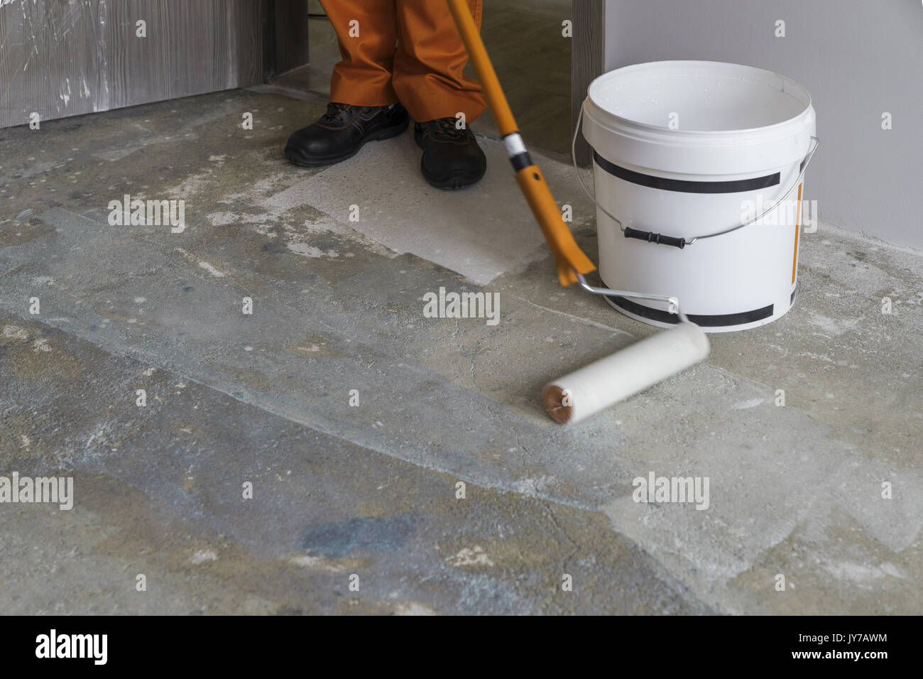 Vacances en construction. Primer avec rouleau travailleur met sur sol en béton Banque D'Images