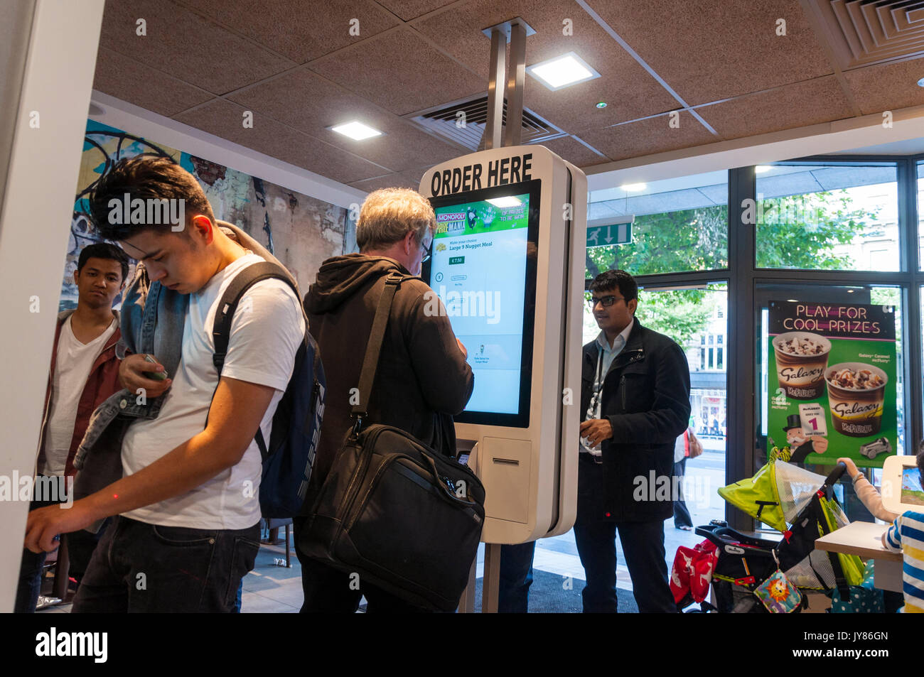 Les gens utilisent des écrans tactiles pour commander des aliments à McDonalds sur O'Connell Street à Dublin, Irlande Banque D'Images