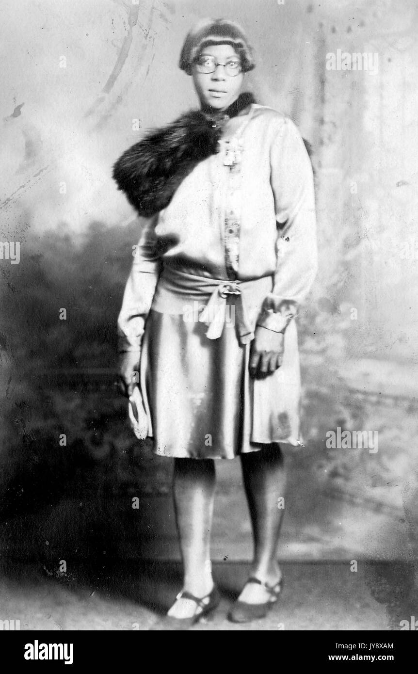 L'article complet portrait of young African American Woman, porter des robe et foulard fourrure, expression faciale neutre, 1920. Banque D'Images