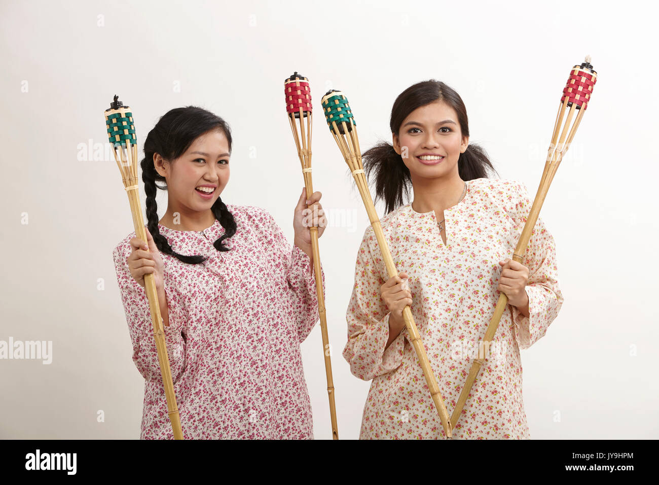 Deux malay woman holding pelita baju kedah sur le fond blanc Banque D'Images