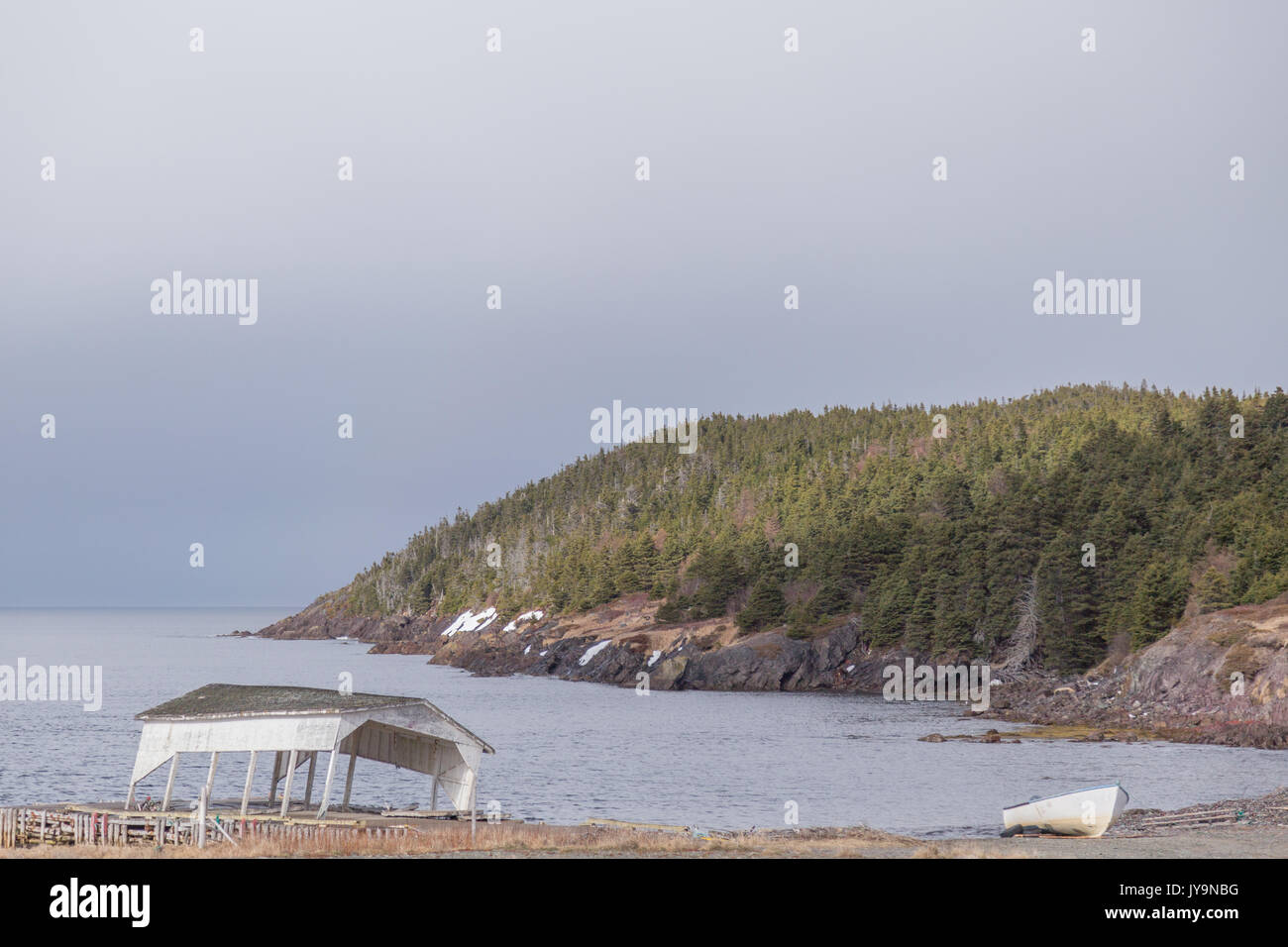 Un gazebo blanc tomber sur un quai de pêche et d'un canot blanc à côté de la mer près de Twillingate, Terre-Neuve, Canada. Le gravier et l'herbe jaune sont scatte Banque D'Images