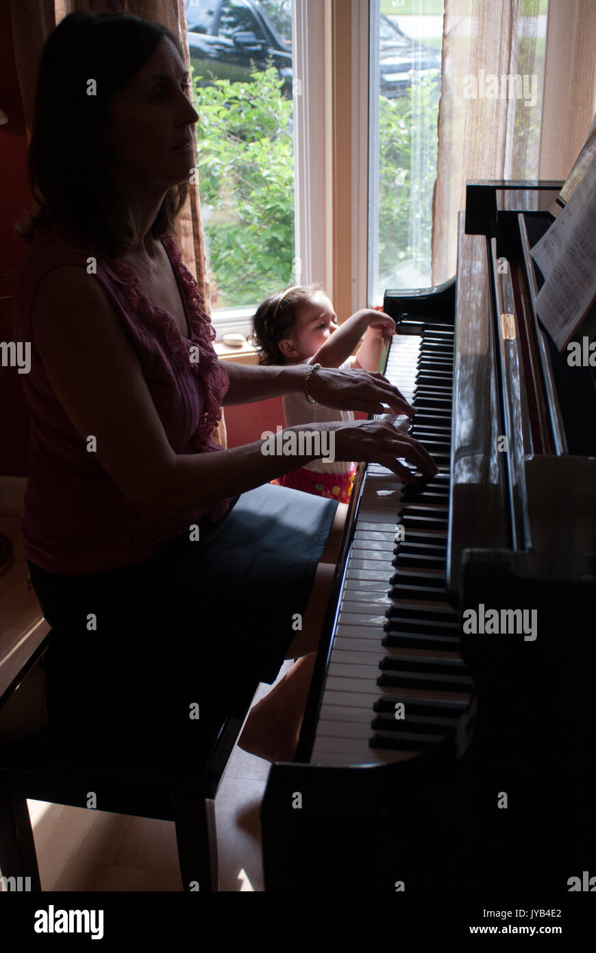 Femme joue du piano tout en un bébé pousse une clé avec un seul doigt Photo  Stock - Alamy