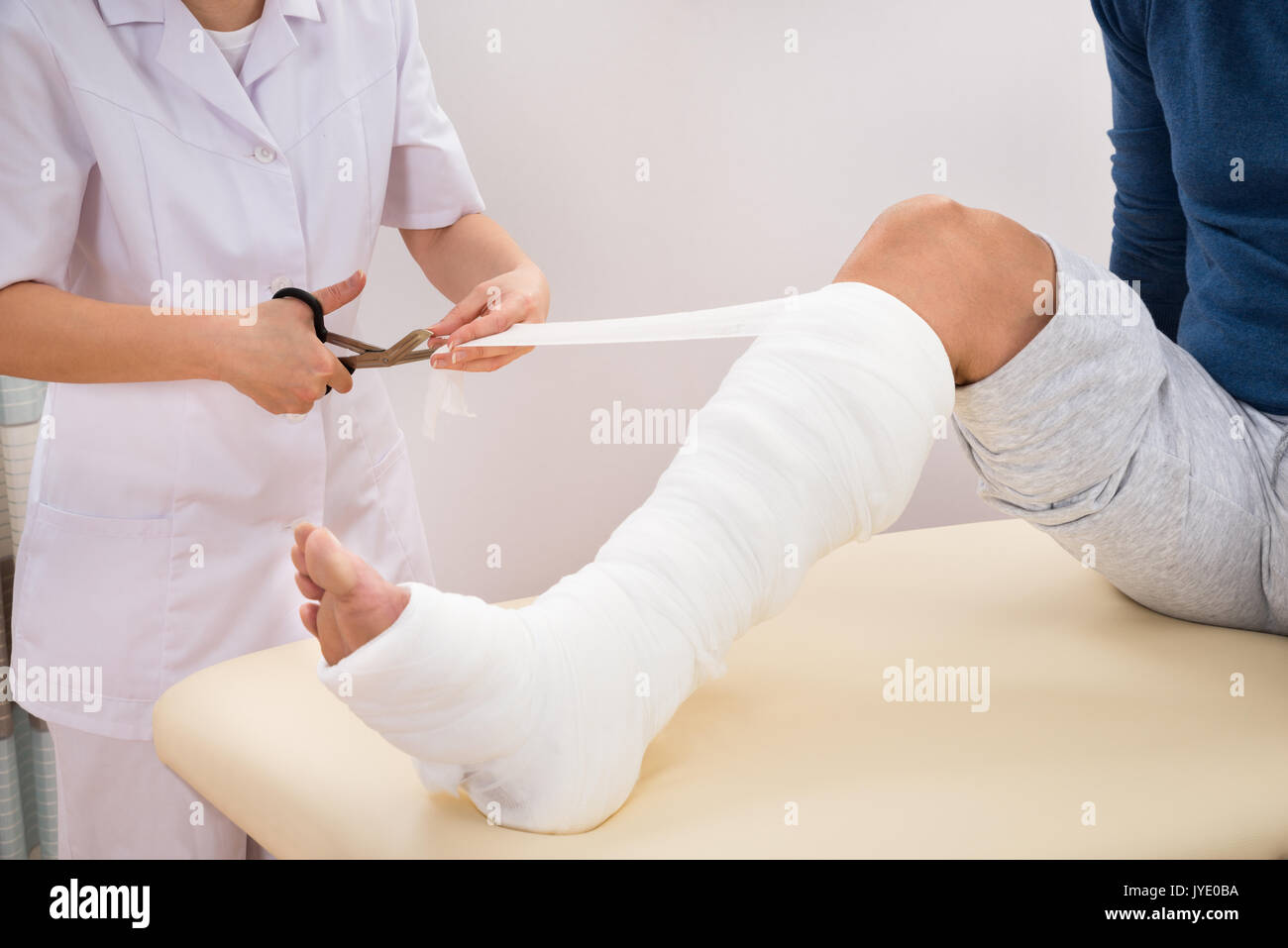 Portrait de femme médecin bandant jambe du patient en clinique Banque D'Images