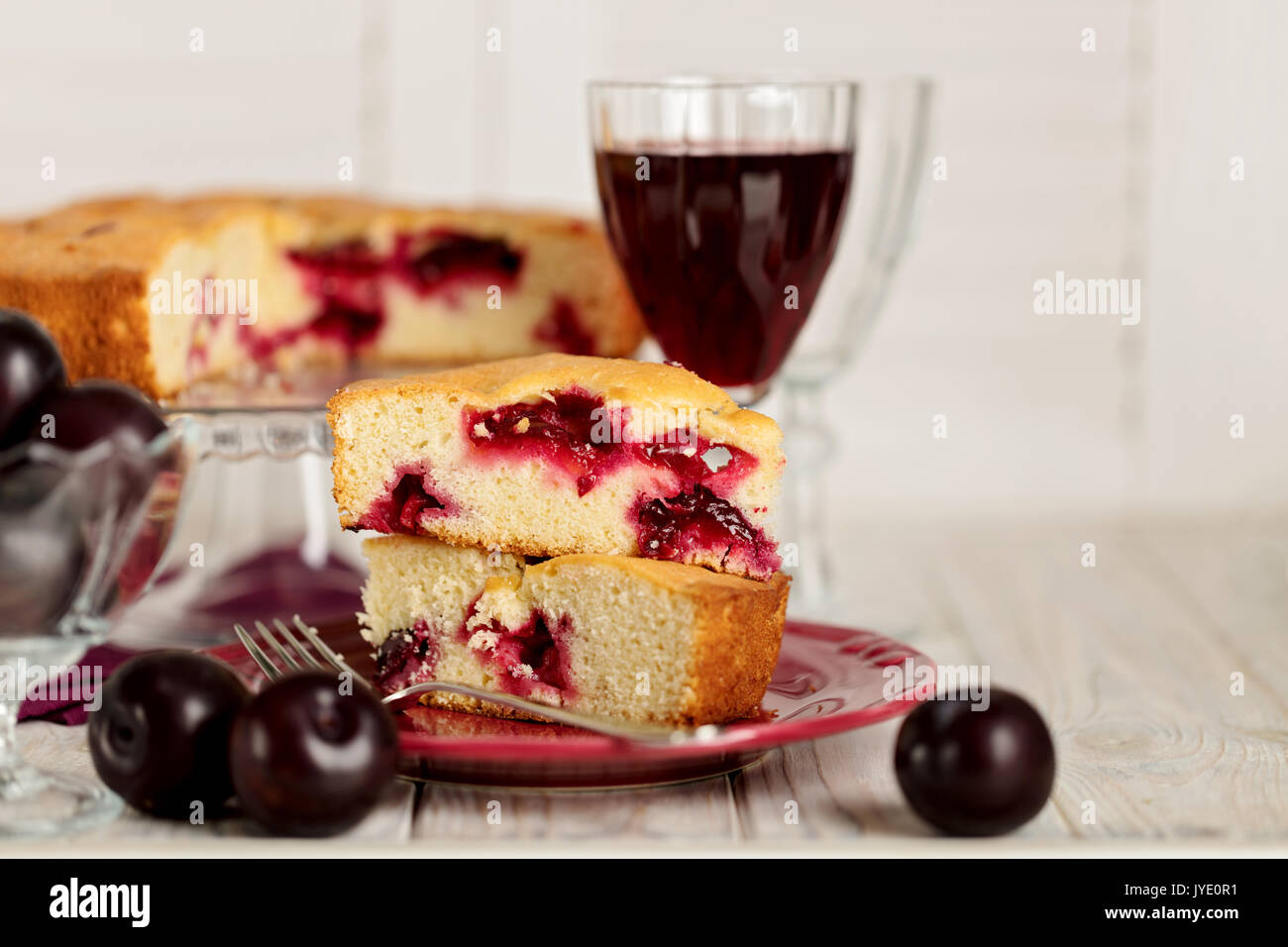 Gâteau aux prunes maison sur un support en verre et vin rouge. Focus sélectif. Banque D'Images