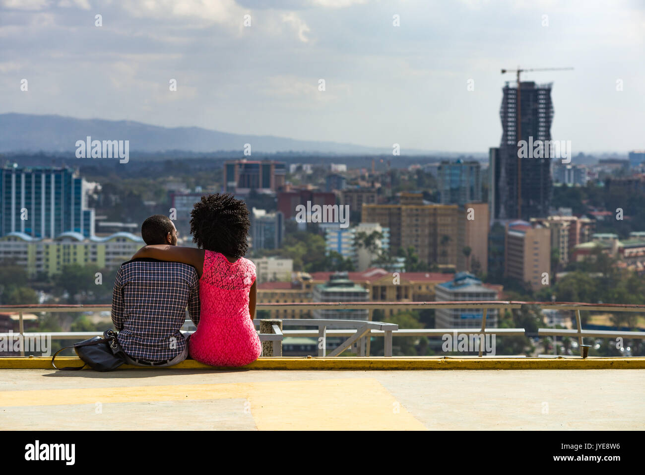 African couple assis en profitant de la vue du Kenyatta International Convention Centre Haut de toit au-dessus de la ville, Nairobi, Kenya Banque D'Images