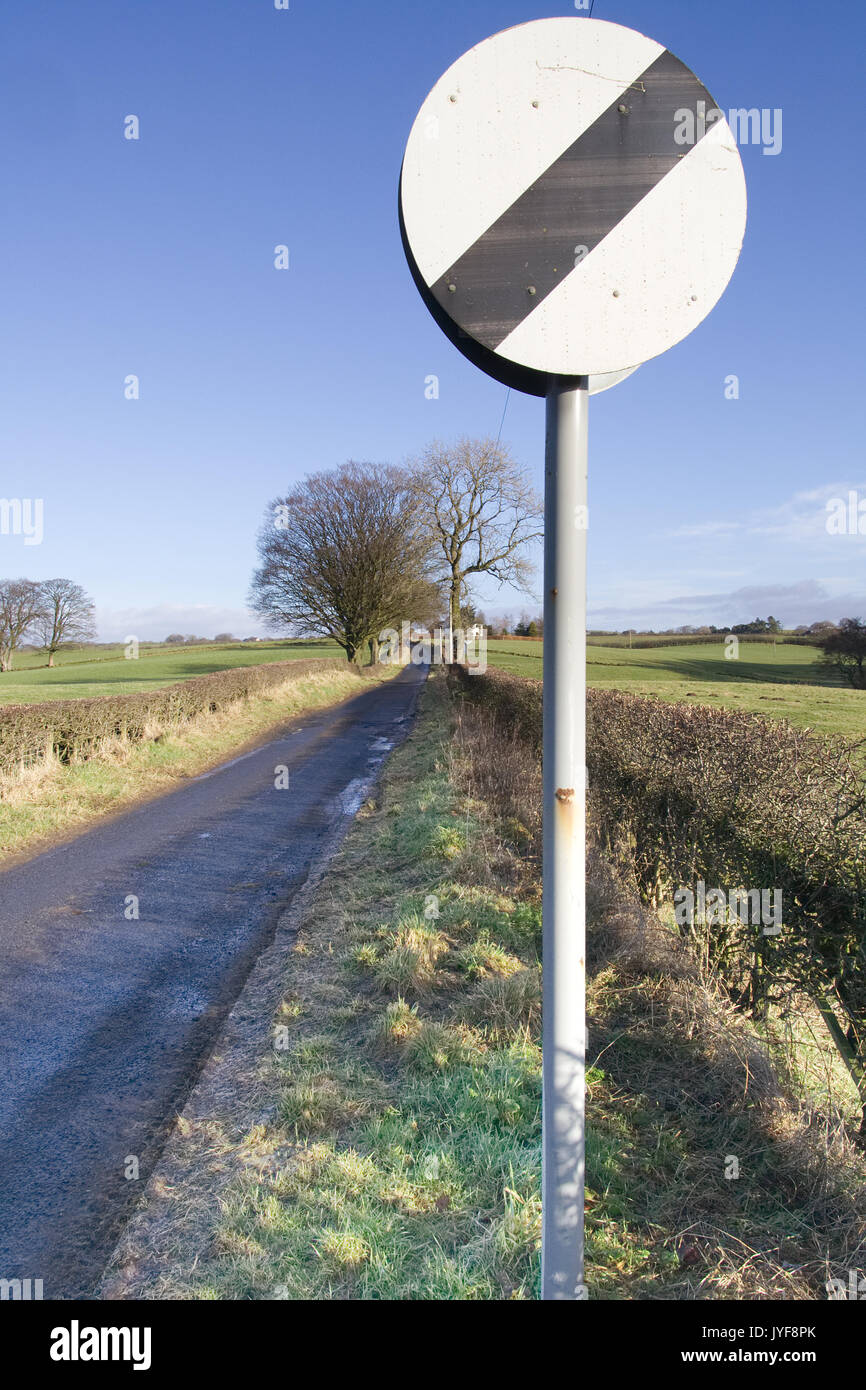 La limite de vitesse nationale signe sur Narrow country Road Banque D'Images