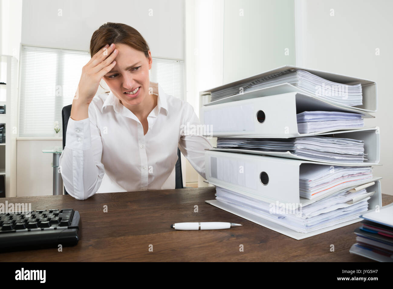 Souligné Young Businesswoman Looking At Pile de Folders In Office Banque D'Images