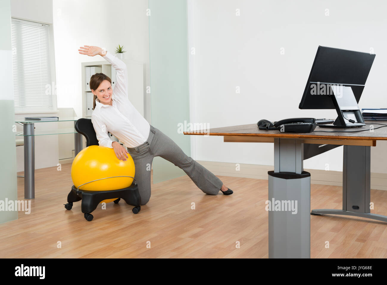 Young Businesswoman faisant Exercice Fitness Pilates ballon jaune sur In Office Banque D'Images