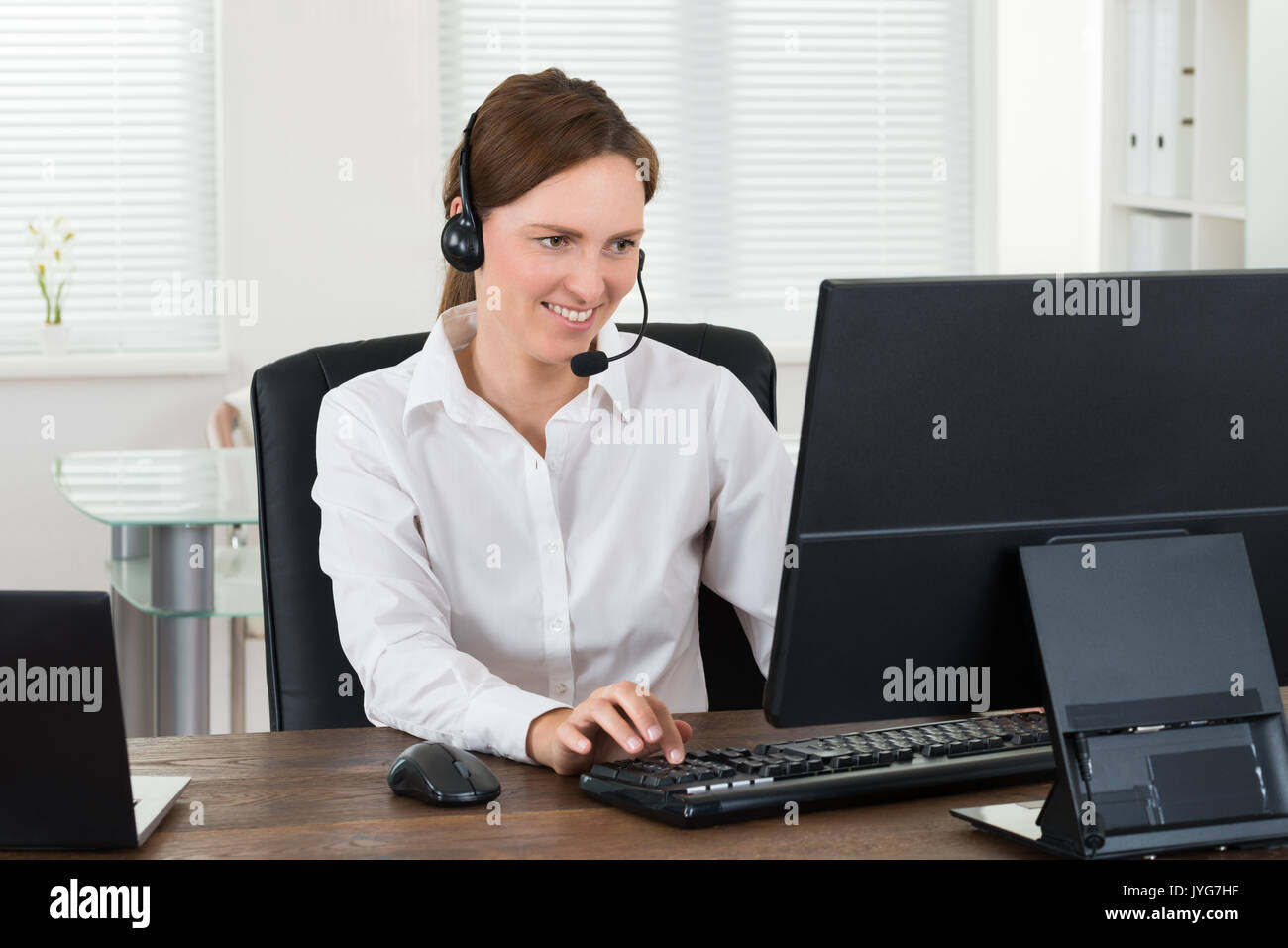 Représentant du service à la clientèle féminine avec casque working on Computer in Office Banque D'Images