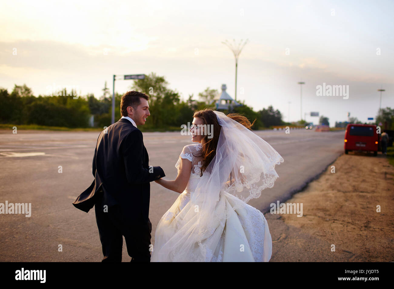 Heureux mariés à l'extérieur de la ville sur la route. Banque D'Images