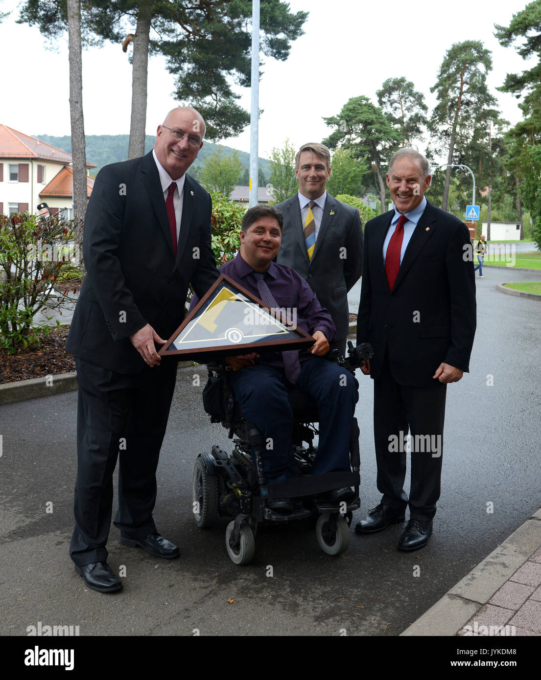 Invictus Games PDG Michael Burns, de concert avec le ministre des Affaires des anciens combattants honorables Kent Hehr et son sous-ministre général (retraité) Walter Natynczyk présenter David Coker, Président de la Fisher House Foundation avec un souvenir Invictus drapeau des Jeux, le 15 août 2017 à la maison de pêcheur près de Centre médical régional de Landstuhl. Les familles des patients comme les Cpl. (Retraité) Chris Klodt, qui a été blessé au combat en Afghanistan, peuvent rester à la maison Fisher à aucun coût tandis que leurs états de service est traité au coût marginal. (U.S. Photo de l'armée par Visual Spécialiste de l'information Elisabeth Paque/R Banque D'Images