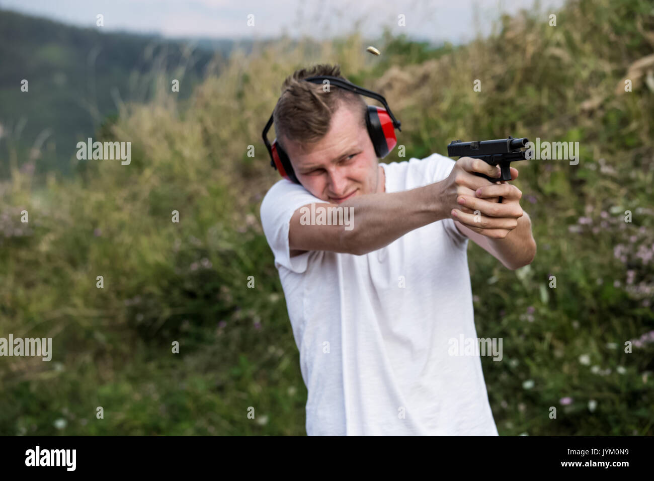 Jeune beau garçon blond de la formation des forces spéciales de police de tir avec le glock pistolet pistolet visant à cibler avec les mains et d'équipement de protection dans la Banque D'Images