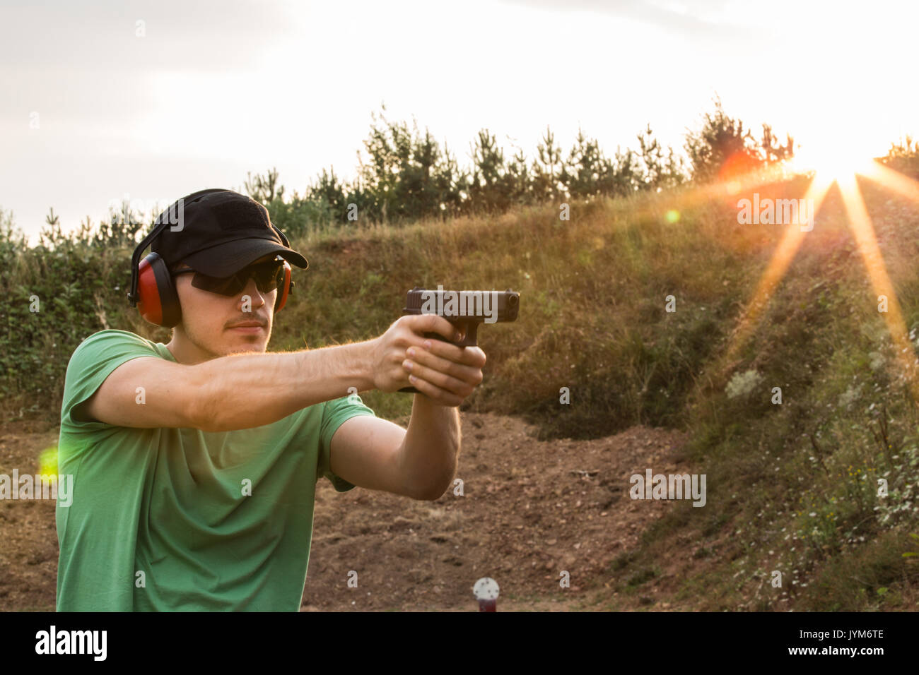 Profil d'un jeune beau policier lors de la formation dans le champ de bataille à l'extérieur de la ville, prêt à prendre les criminels et le tir avec l'arme glock p Banque D'Images
