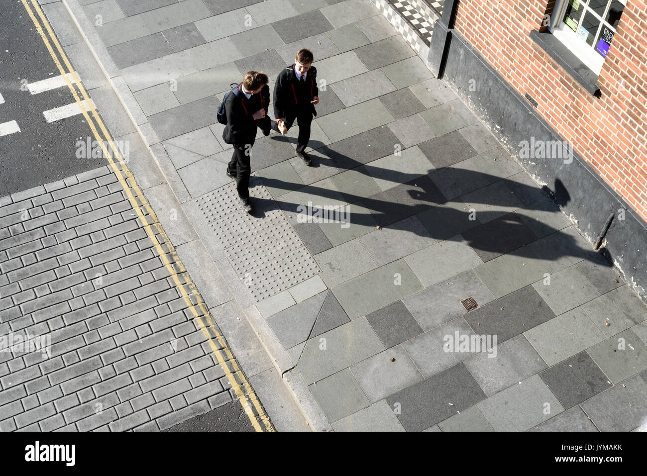 Deux enfants de l'école balade le long d'un sentier piétonnier avec de fortes ombres contraste élevé provenant d'un arieal directement l'image ci-dessus Banque D'Images