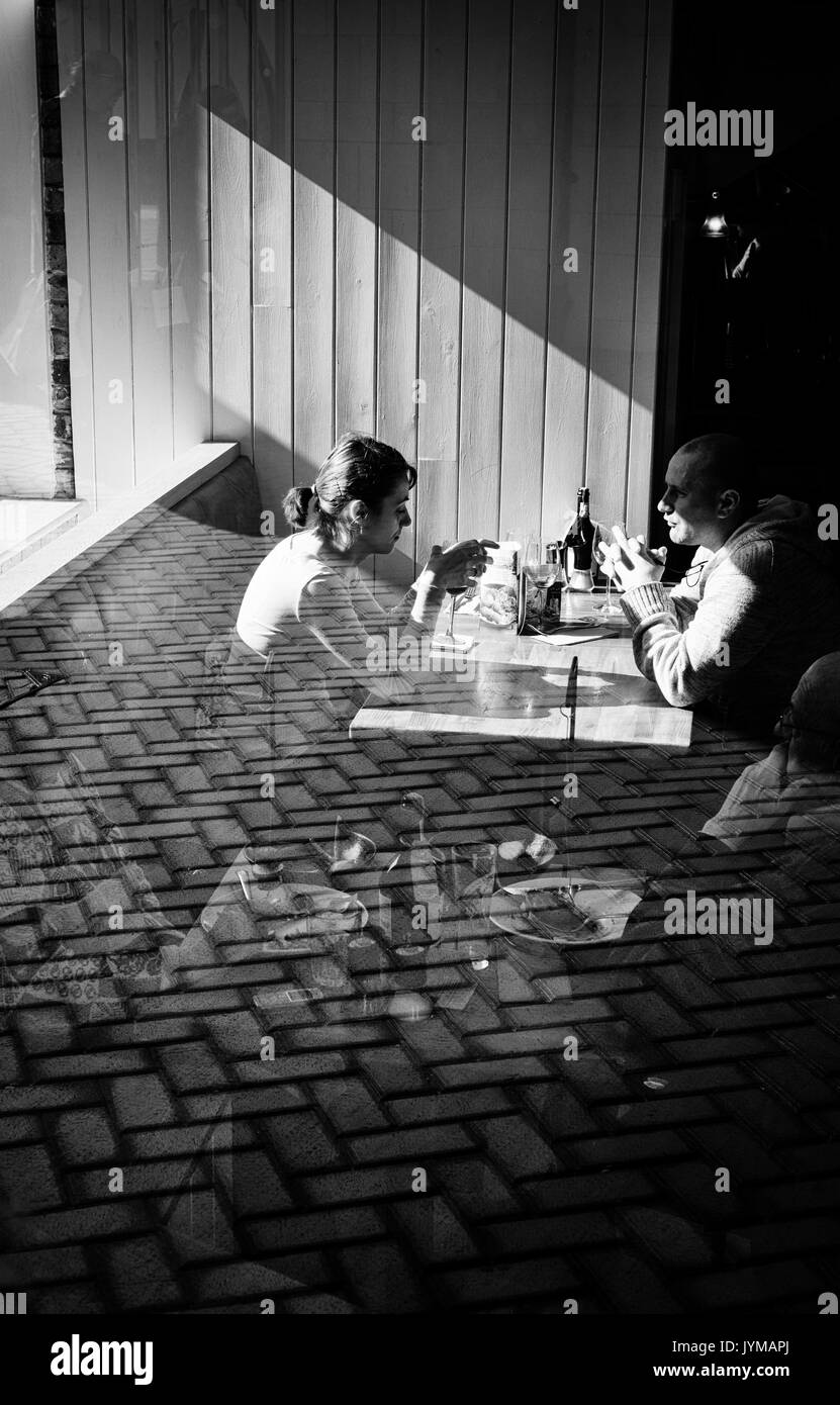 Homme et femme couple s'asseoir dans un restaurant à une table avec la réflexion de la fenêtre en verre Banque D'Images