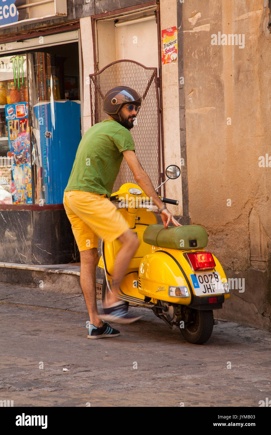 Man getting sur scooter jaune jaune portant des shorts et tee-shirt vert à Tolède, Espagne Banque D'Images
