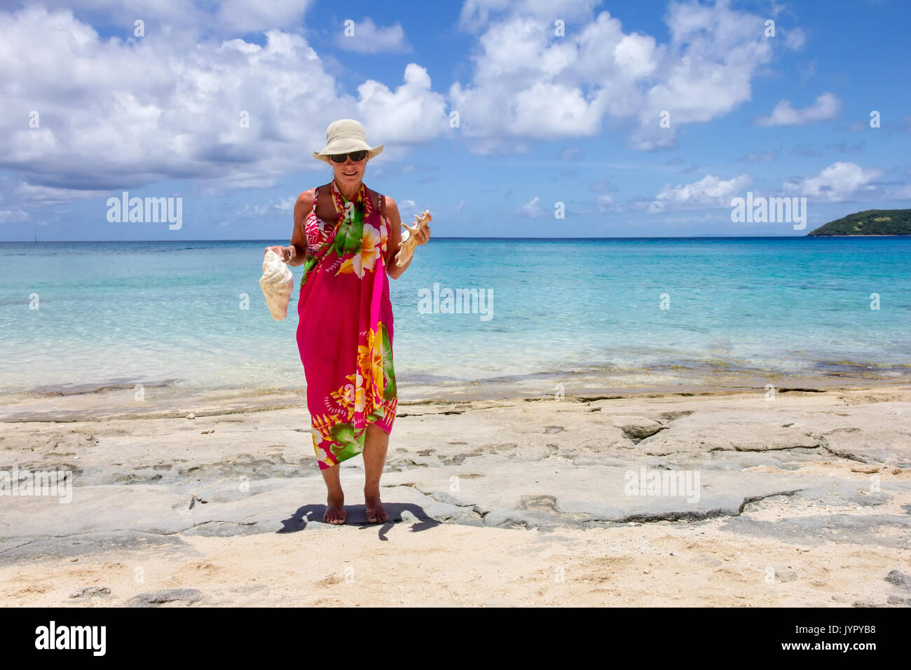 Senior woman holding conques sur Dravuni Island beach, Fidji, Pacifique Sud Banque D'Images