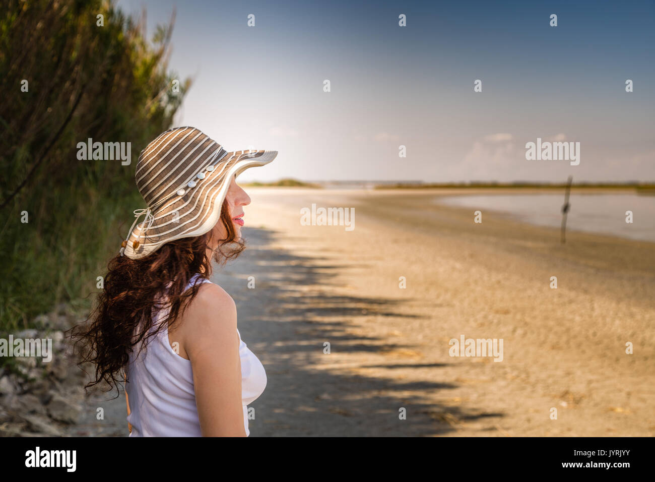 Vue latérale du beau busty mature femme en très bon état avec large hat smiling sur une plage de split Banque D'Images