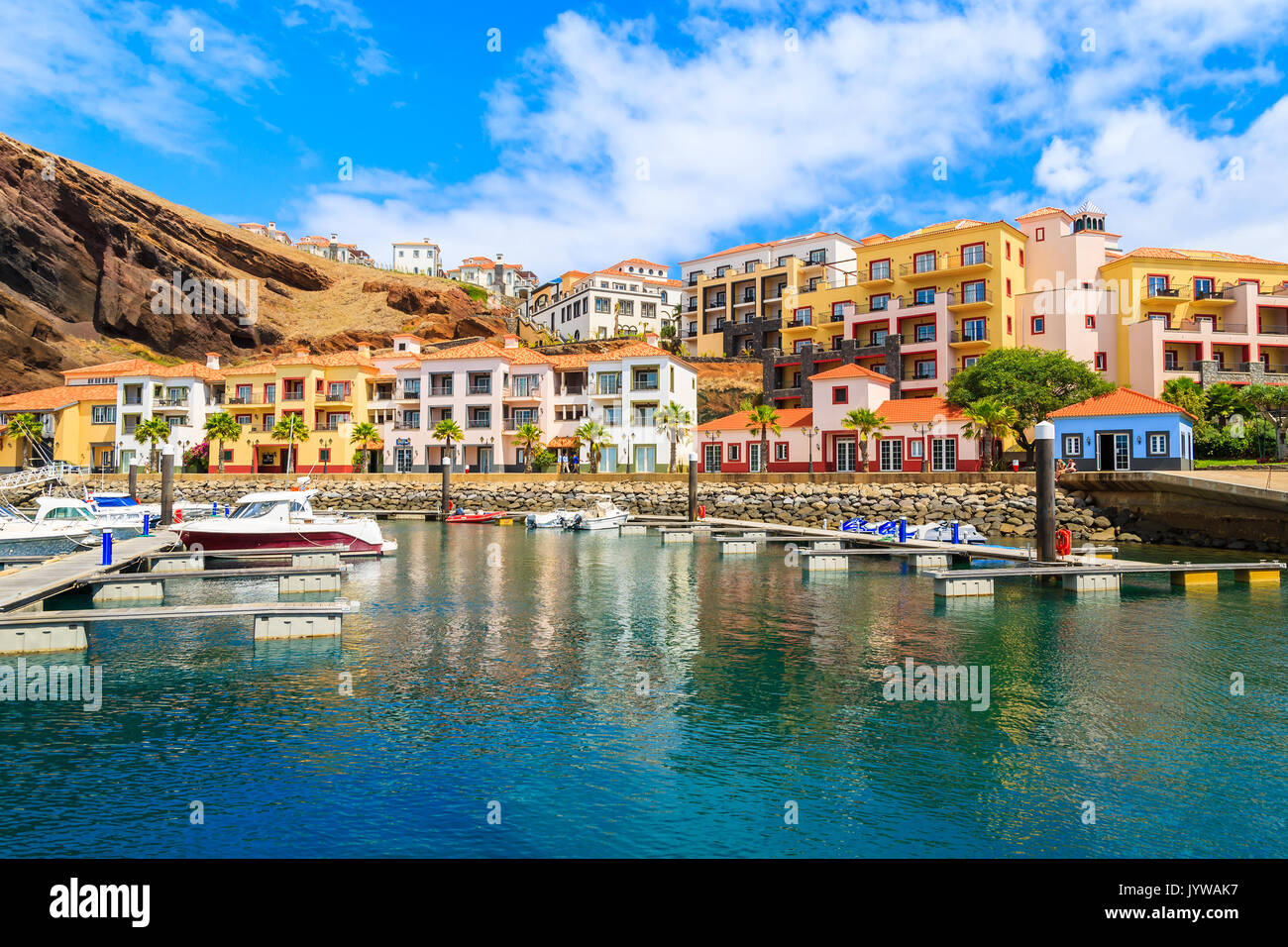 Bateaux dans marina avec ses maisons colorées près de Canical ville sur la côte de l'île de Madère, Portugal Banque D'Images