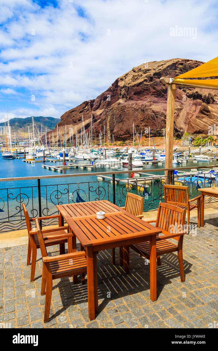Table de restaurant en terrasse au port de plaisance sur la côte de l'île de Madère, Portugal Banque D'Images