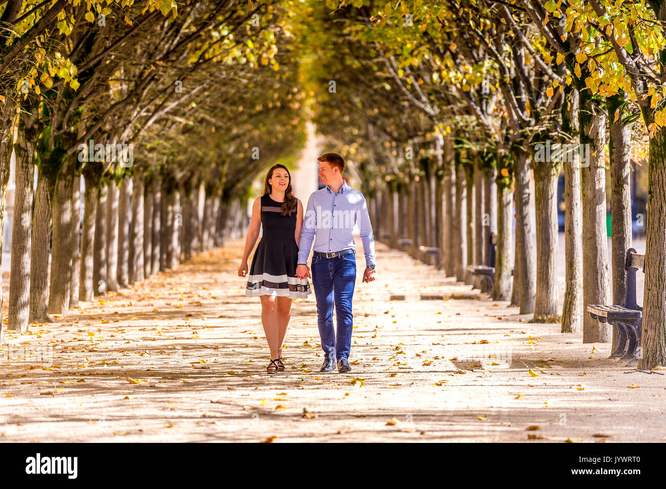 Couple marche main dans la main entre les rangées d'arbres dans le Jardin du Palais Royal à Paris Banque D'Images