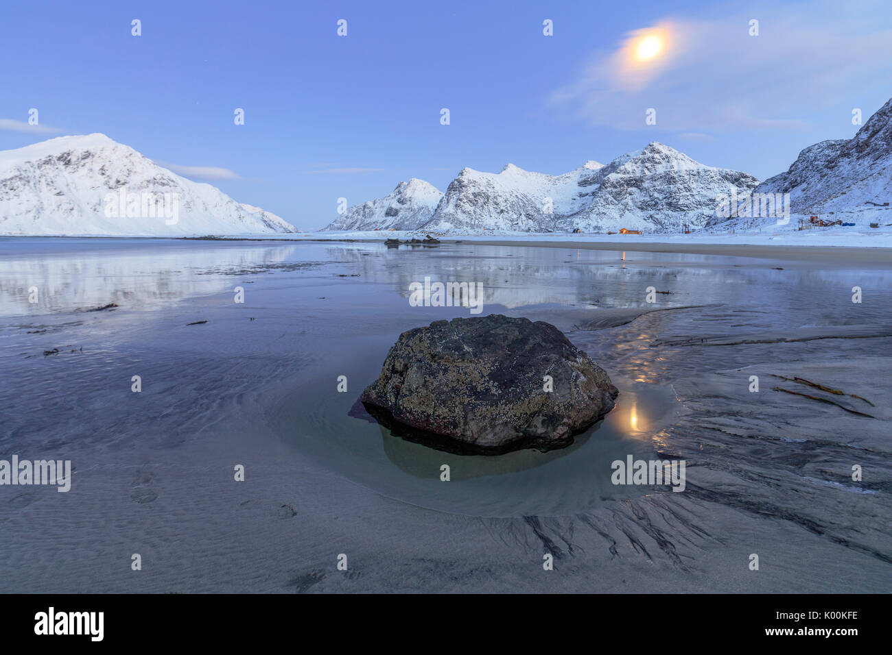 Pleine lune reflétée dans la mer de glace autour de la plage de Skagsanden surréaliste Flakstad Nordland County Iles Lofoten Norvège Europe Banque D'Images