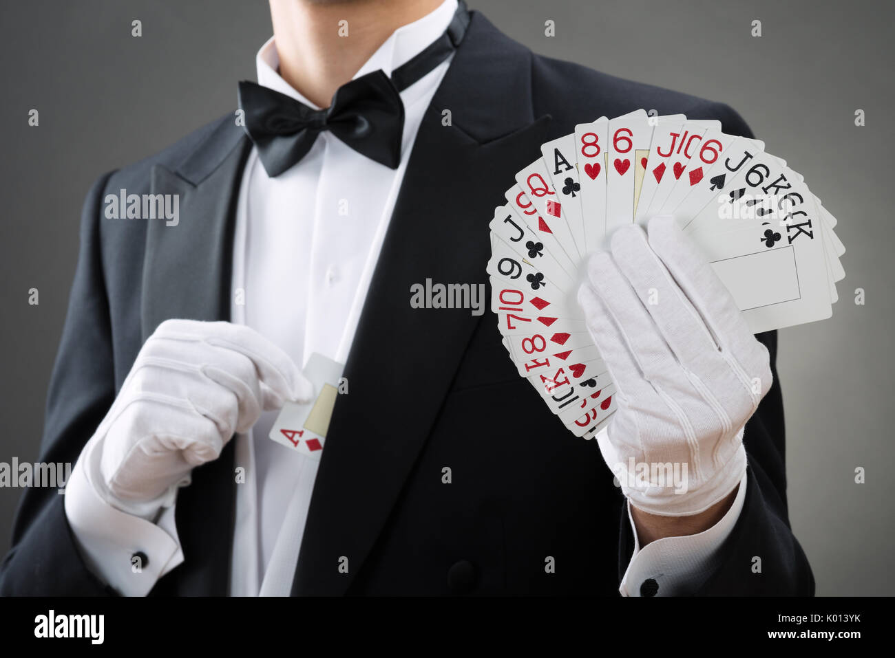 Au milieu du magicien montrant se déploient en cartes contre fond gris Banque D'Images