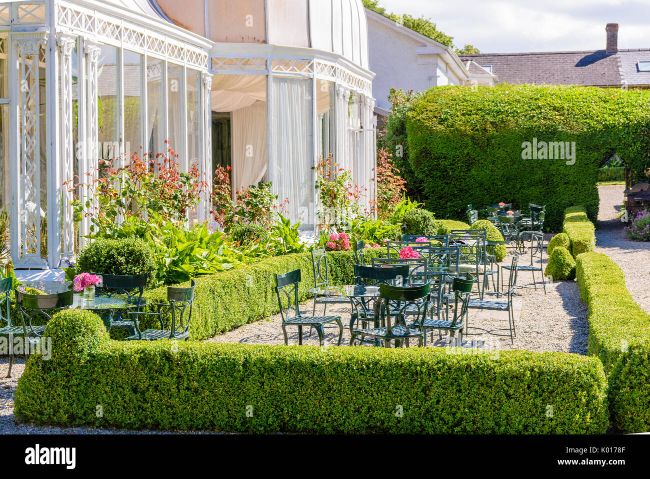Les tables d'un jardin à l'extérieur de l'entrée de l'hôtel à la lumière du soleil. Banque D'Images