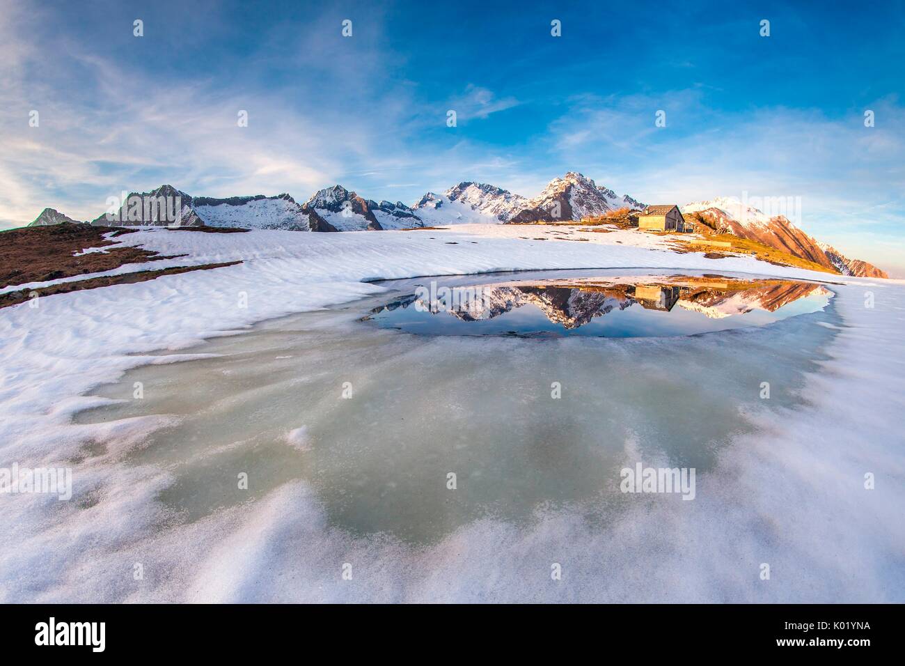 Scermendone dégel du lac au cours reflétant le mont Disgrazia au coucher du soleil, de la Valteline Sondrio, Lombardie, Italie. L'Europe Banque D'Images