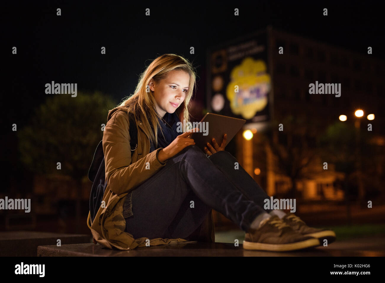 Femme dans la ville la nuit holding tablet, lire quelque chose. Banque D'Images
